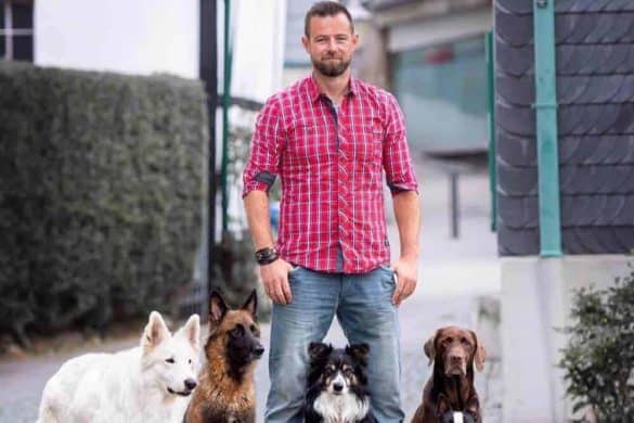 André Vogt posiert mit vier Hunden auf einer Straße.