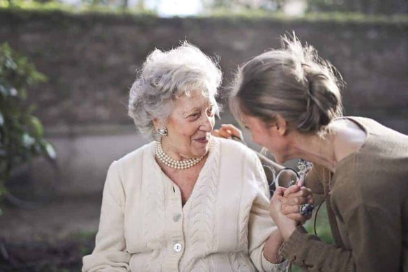 Eine jüngere Frau hält eine ältere Dame am Handgelenk fest, aber beide lachen.