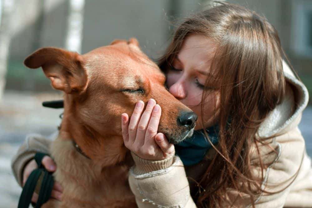 Eine junge Frau kuschelt mit einem Hund.