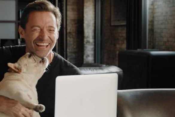 Hugh Jackman mit seinem Hund "Dali" lachend am Laptop.