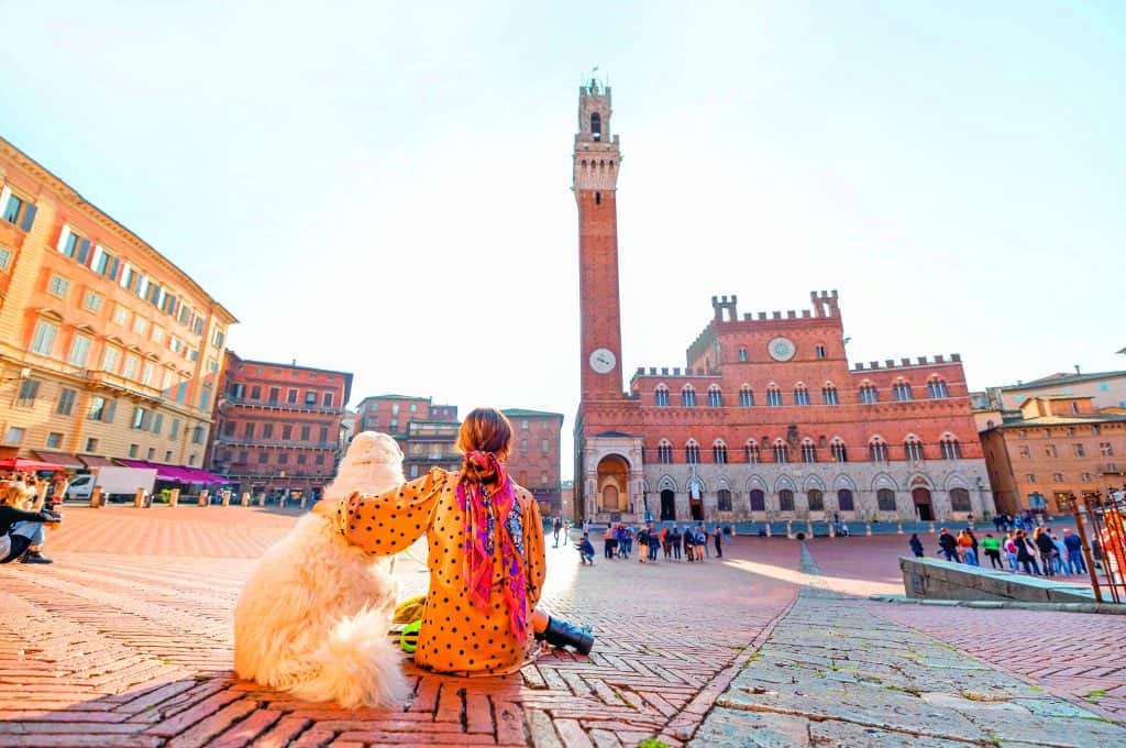 Frau mit Hund im Urlaub. Sie sitzen am Siena
