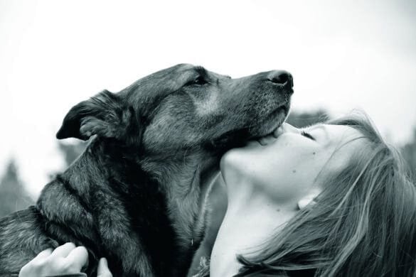 Nahaufnahme einer Frau, die ihren Hund liebevoll küsst, in Schwarz-Weiß. Perfekt für Tierliebhaber und Hundebesitzer, die die besondere Bindung zu ihren Vierbeinern zeigen möchten.